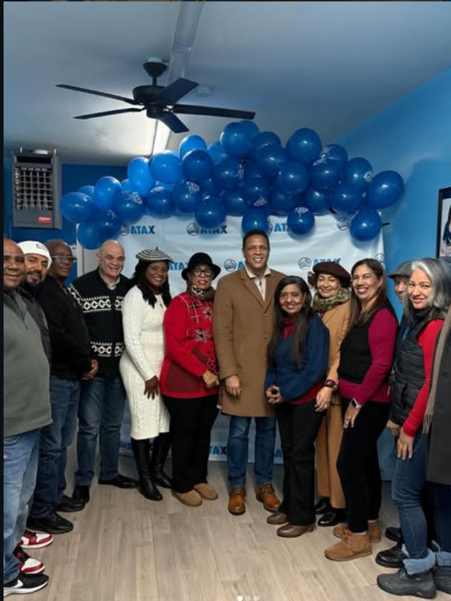 A group gathered in front of an ATAX backdrop